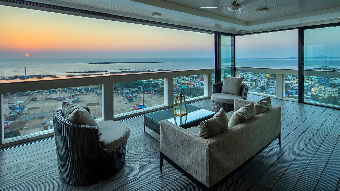 A glass-walled lounge overlooking the sea at sunset