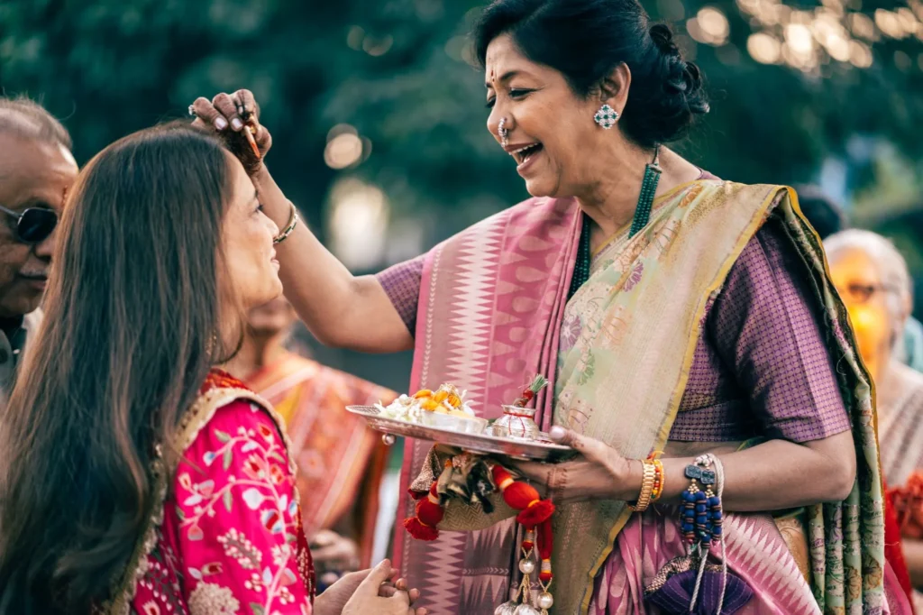 A laughing elder blesses the bride with a tilak