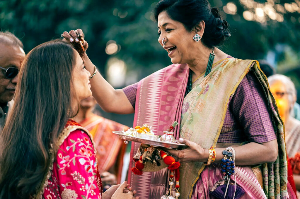 A laughing elder blesses the bride with a tilak
